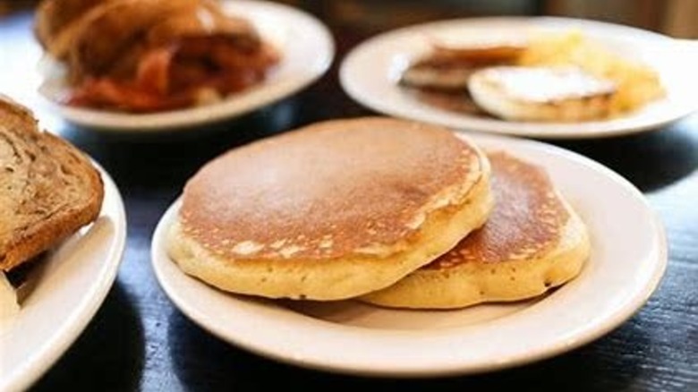 Pancake plate with other various breakfast plates blurred in the background at Creek House Diner