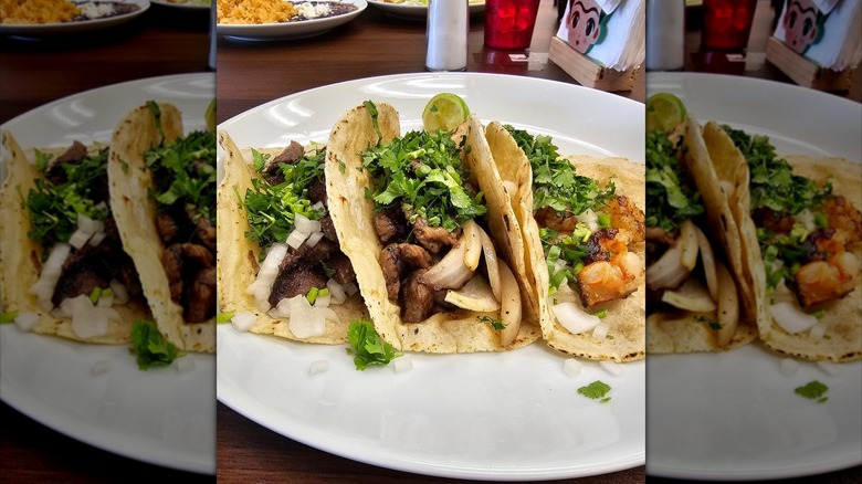 Three tacos on plate with homemade tortillas: lengua, asada, and camarón at Salsa Oaxaqueña restaurant