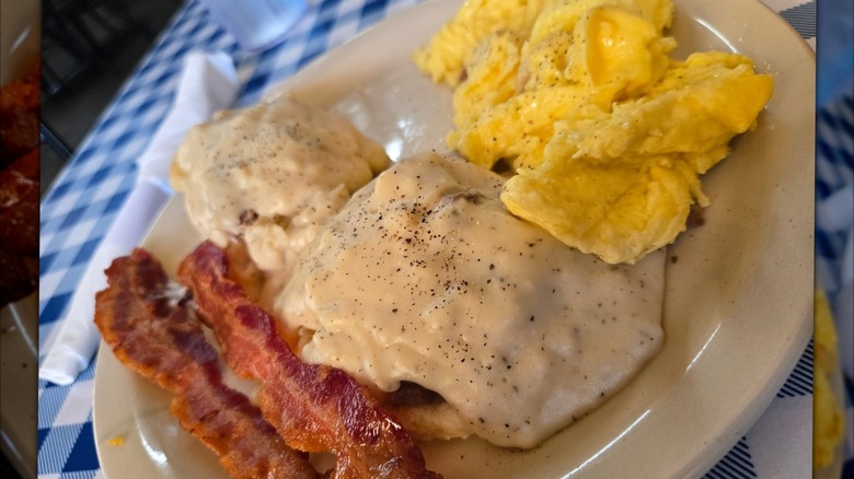 Biscuits and Gravy with bacon and scrambled eggs on plate at H&H Soul Food Restaurant