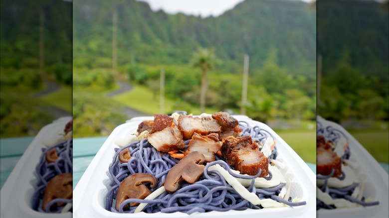 Ube noodles in takeout box from Adela's Country Eatery with Hawaii mountains blurred in background