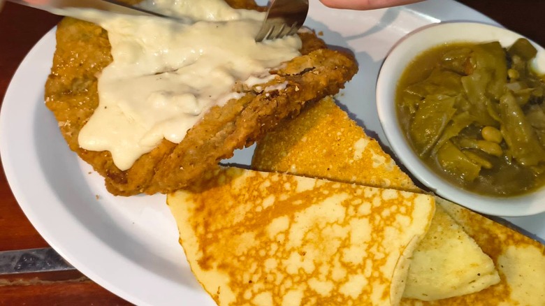 Country fried steak, green beans, and cornbread on plate at The Whistle Stop restaurant