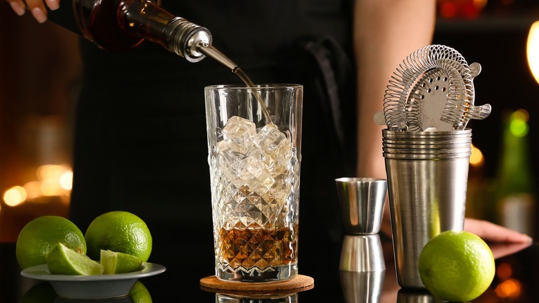 Bartender preparing Long Island iced tea with limes nearby