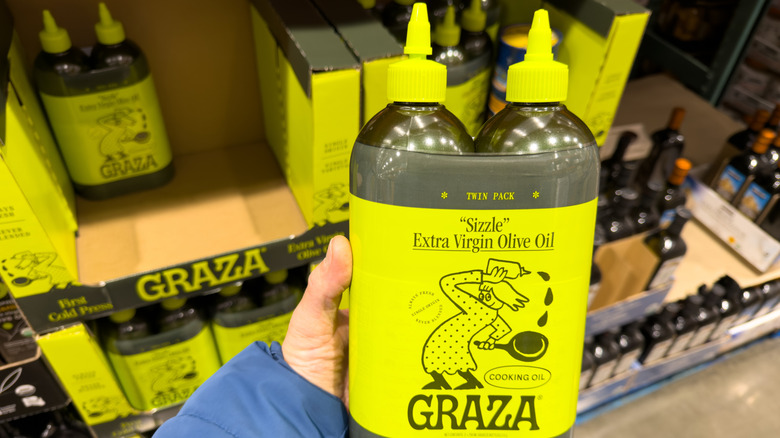 A hand holding a two-pack of Graza Sizzle extra virgin olive oil at Costco
