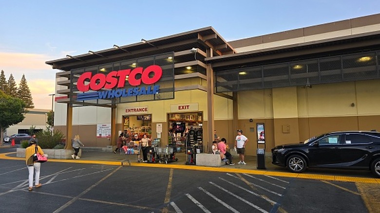 Exterior of a Costco at dusk, shoppers exiting and entering