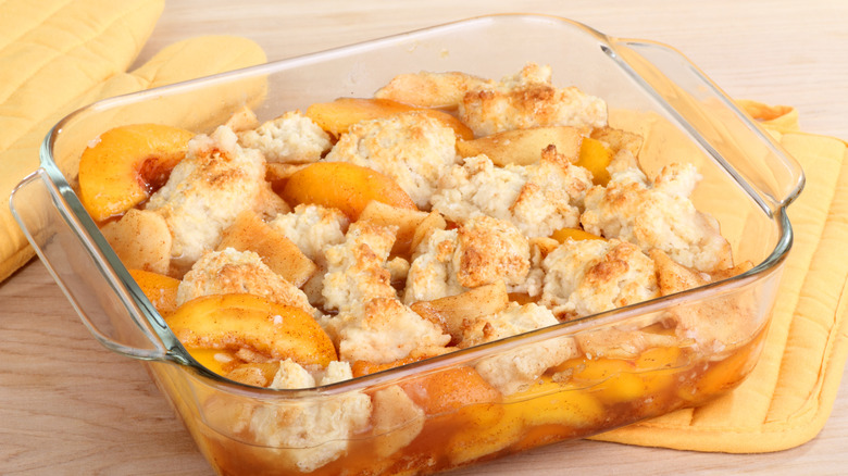 A baked peach cobbler in a glass dish