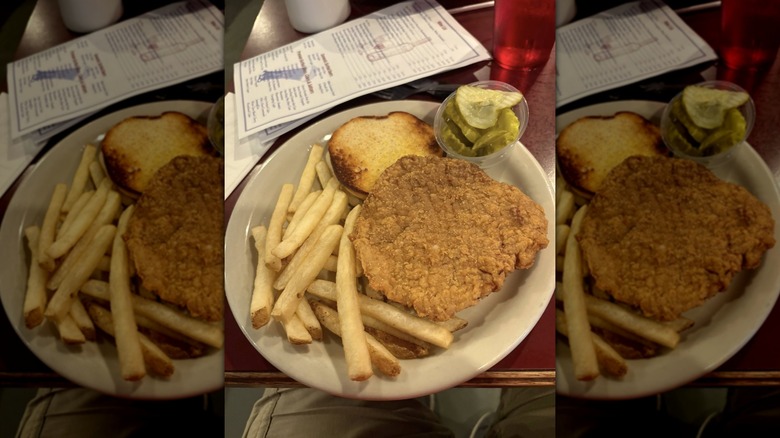 Friendly Tavern Pork Tenderloin Sandwich with side of fries and mini pickle slices
