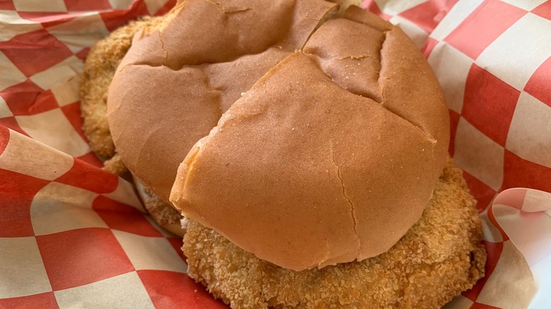 A pork tenderloin sandwich on red-and-white checkered paper