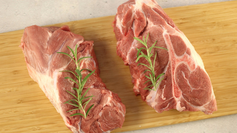 Raw Boston pork butt steaks on a wooden board