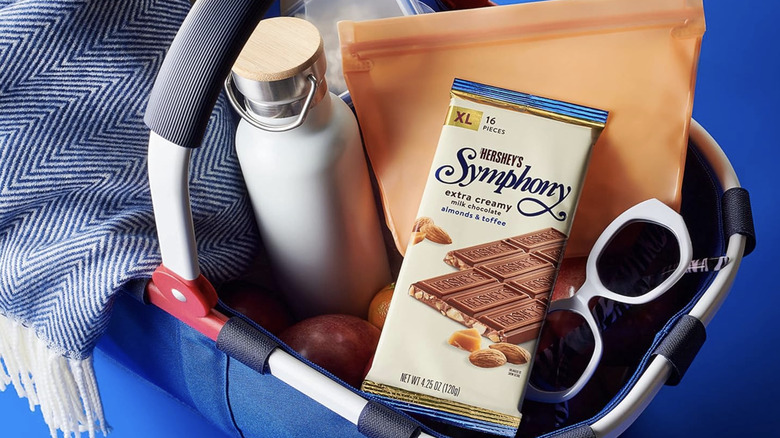 A Hershey's Symphony Milk Chocolate Bar placed on top of a stylish blue picnic basket with other goods.