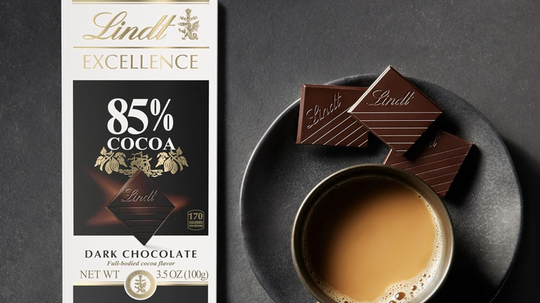 Lindt Excellence Dark Chocolate Bar served with a cup of coffee over dark surface.
