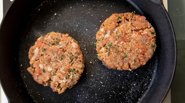 uncooked salmon patties in a black frying pan