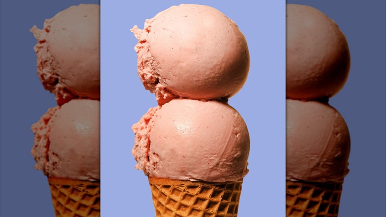 Two scoops of Van Leeuwen strawberry ice cream on a waffle cone