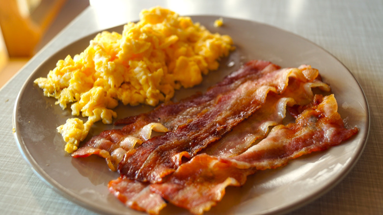 scrambled eggs and bacon on a beige plate