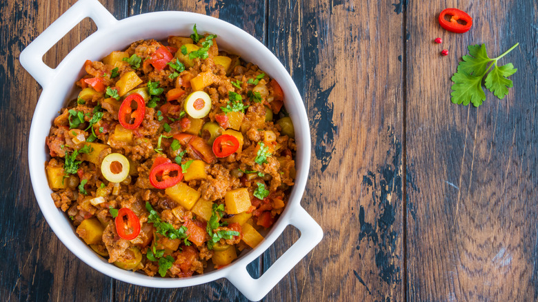 Cuban-style picadillo in a white pot on a wooden surface