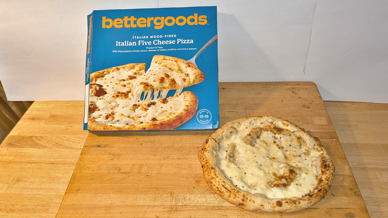 Bettergoods Italian Five Cheese Pizza cooked on cutting board next to package.