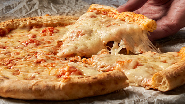 Hand reach for slice of cheese pizza