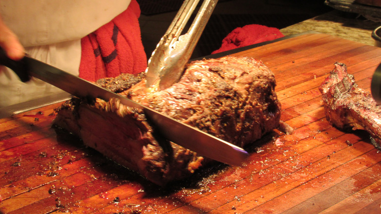 A worker carving up meat at a buffet station