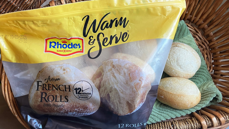 a bag of Rhodes Warm & Serve Artisan French Rolls in a basket with two baked rolls