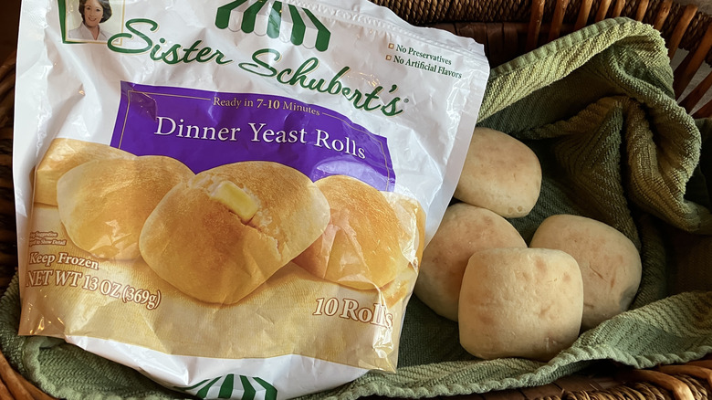 a bag of Sister Schubert's frozen dinner rolls in a basket with baked rolls