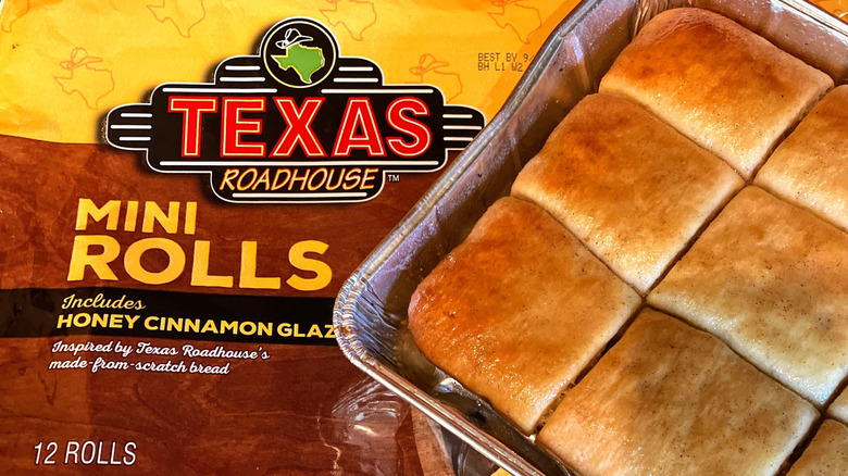 a pan of glazed rolls sits on top of a brightly colored bag of Texas Roadhouse mini rolls