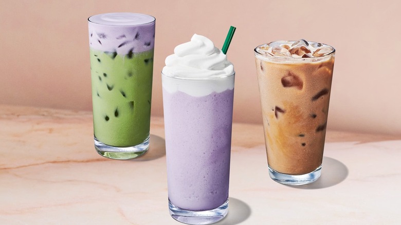 Three new spring drinks from Starbucks on a light pink, marbled surface.