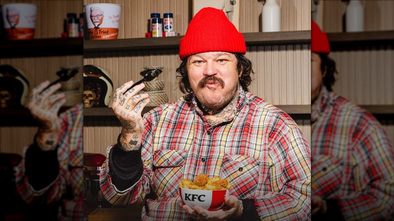 Matty Matheson poses with a KFC bowl with KFC memorabilia in the background