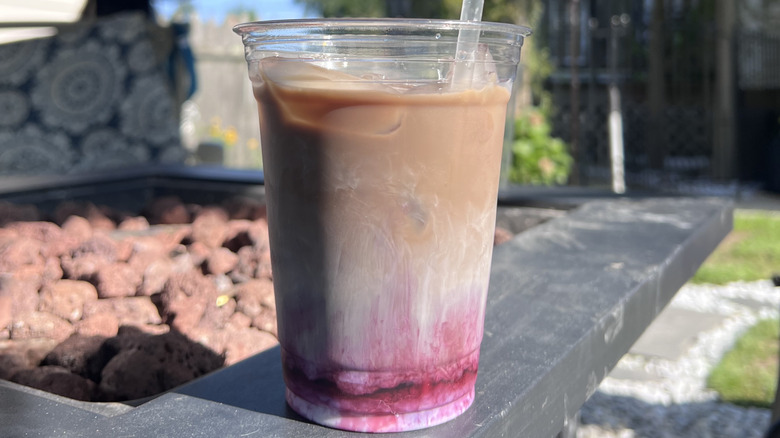 Candid photo of iced blueberry latte in a plastic cup outside