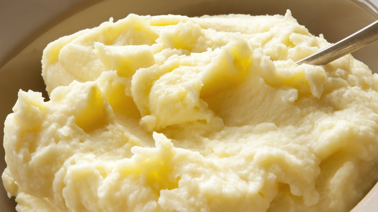 Close up of bowl of fluffy mashed potatoes with spoon in them