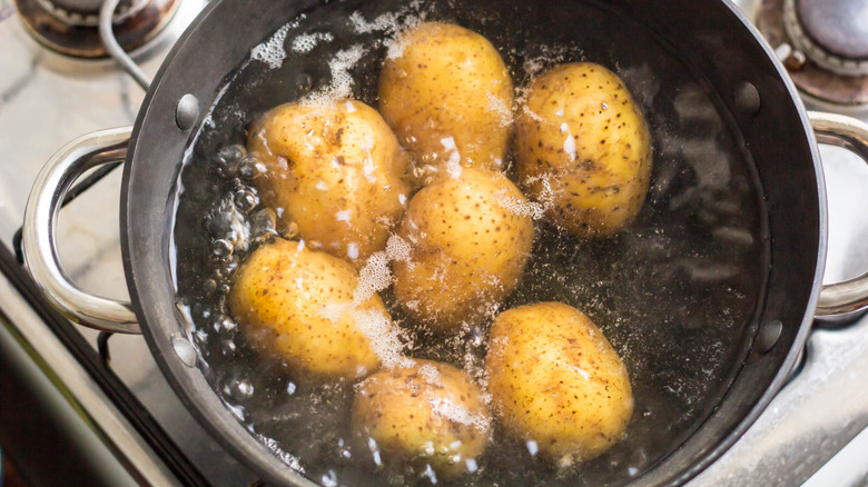 Seven potatoes in pot of boiling water on a stove