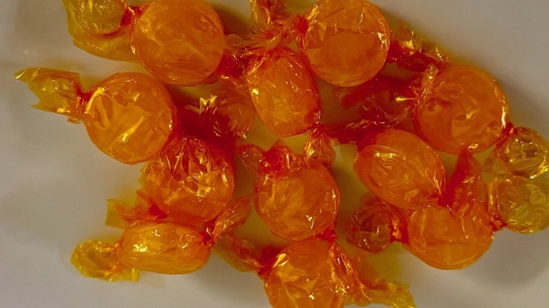 Round, yellow plastic wrapped candies on a white plate