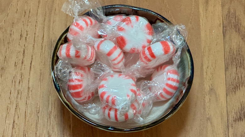 A small bowl filled with red and white wrapped peppermints