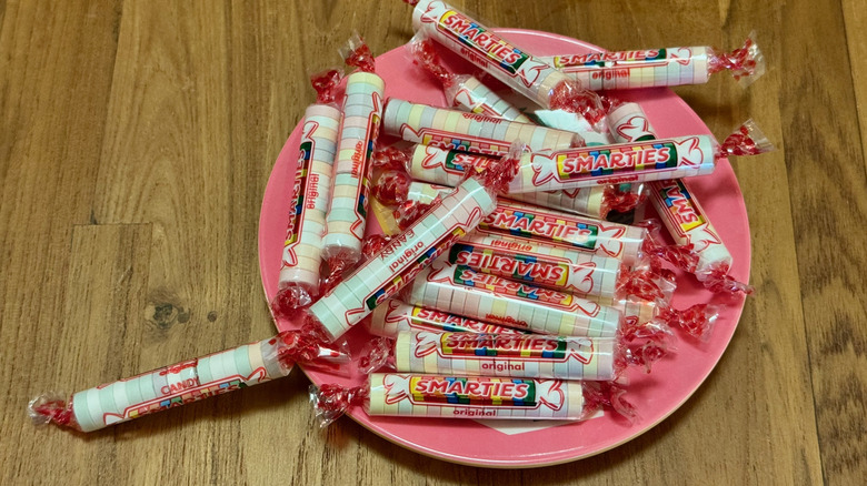 A small pink plate stacked with packages of Smarties