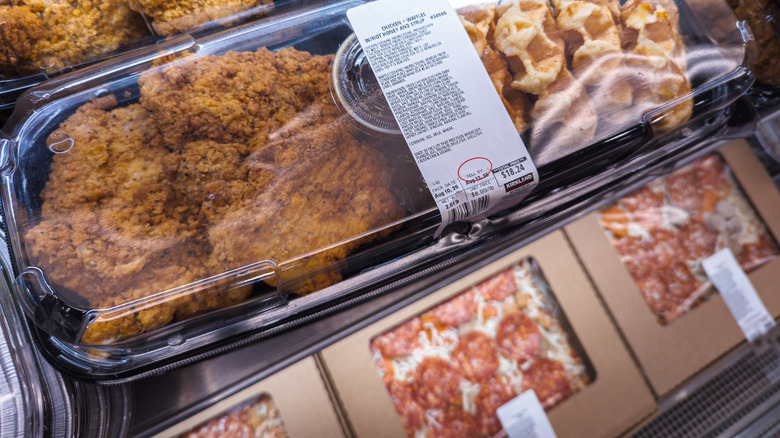 The premade food shelf at a Costco, with pre-packaged pizzas and chicken and waffles.