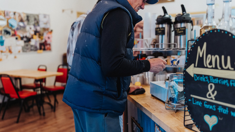 Older man paying for coffee at a coffee shop