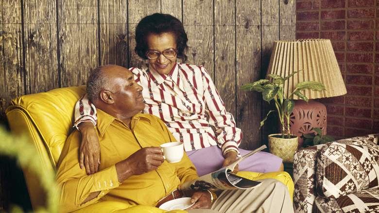 A couple from the 1970s sitting and drinking coffee on the couch