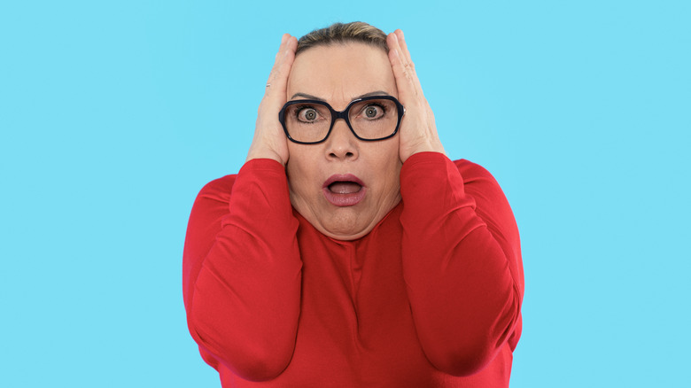 A woman exaggeratingly covering her ears