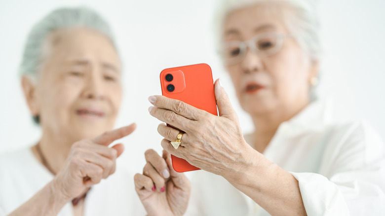 Two older woman trying to figure out a smartphone