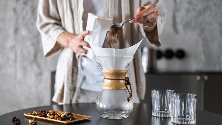 closeup of male hands with spoon prepare fresh coffee in glass chemex