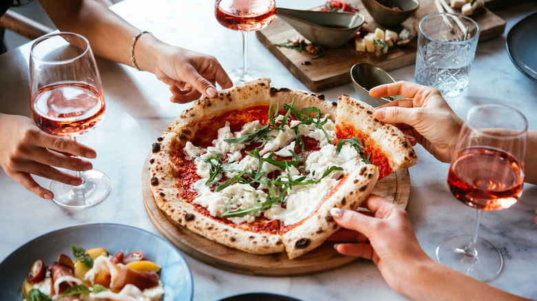 Pizza, caprese salad, and glasses of rose wine at an Italian restaurant