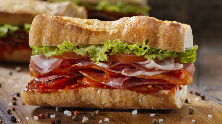 Italian sub sandwich with red peppers on a wooden board