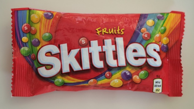 A bag of Skittles on a beige background.