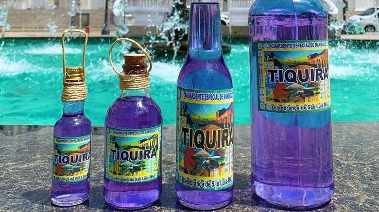 Four bottles of Tiquira in front of a pool.