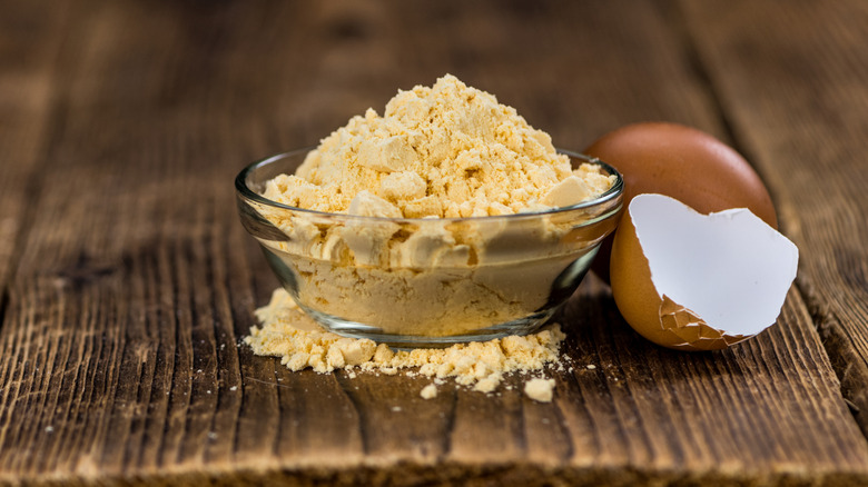A small bowl of powdered eggs next to an eggshell