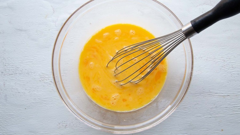 Beaten eggs in bowl with whisk