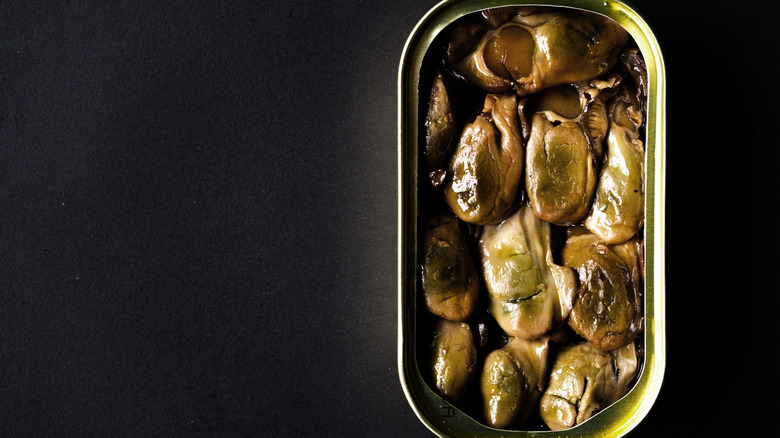 Close-up of an open can of smoked oysters on a black background