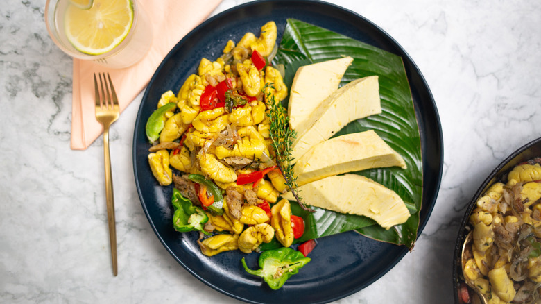 A plate of ackee and saltfish with breadfruit and green scotch bonnet peppers