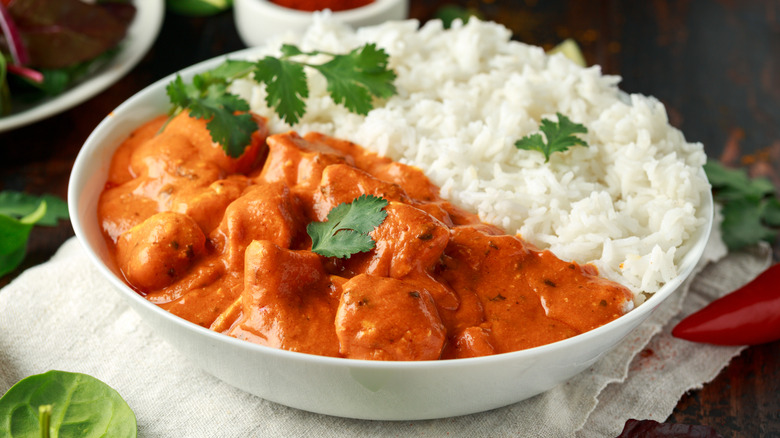 A bowl of chicken tikka masala served with white rice.
