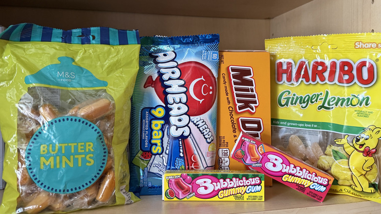 a kitchen cabinet filled with candies like butter mints, airheads, milk duds, Haribo gummy bears, and two packs of Bubblicious Gummy Gum.