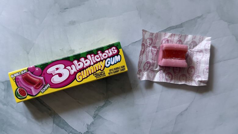 Pack of Bubblicious Gummy Gum in watermelon flavor next to an unwrapped piece of gum on countertop