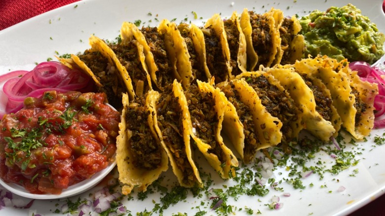A platter filled with broccoli cheddar mini tacos, salsa, and guacamole